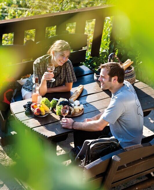 Junges Paar genießt regionale Köstlichkeiten auf Terrasse im Weinberg