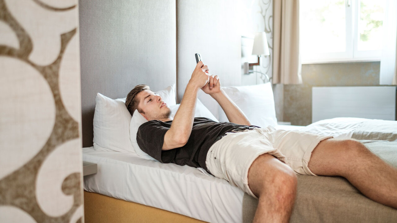 youtube Video Thumbnail: Mann liegt mit Smartphone auf Hotelbett